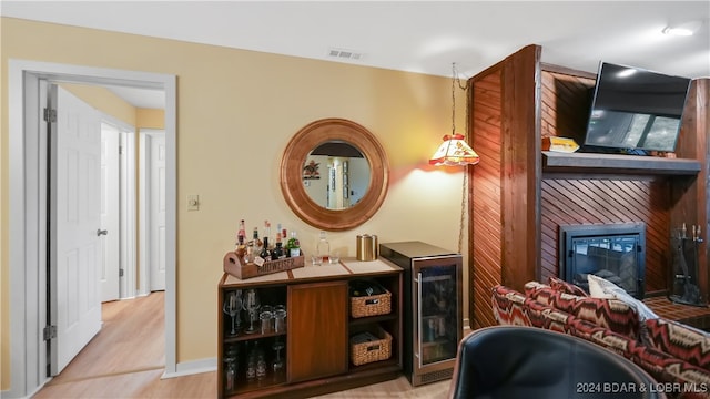 bar featuring a large fireplace, pendant lighting, and light wood-type flooring