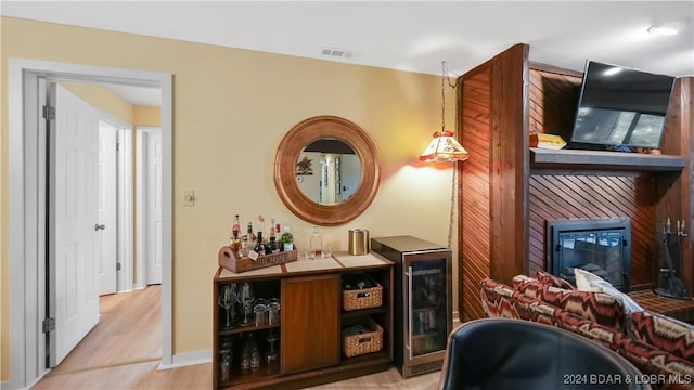 bar featuring a large fireplace, wood finished floors, visible vents, and baseboards