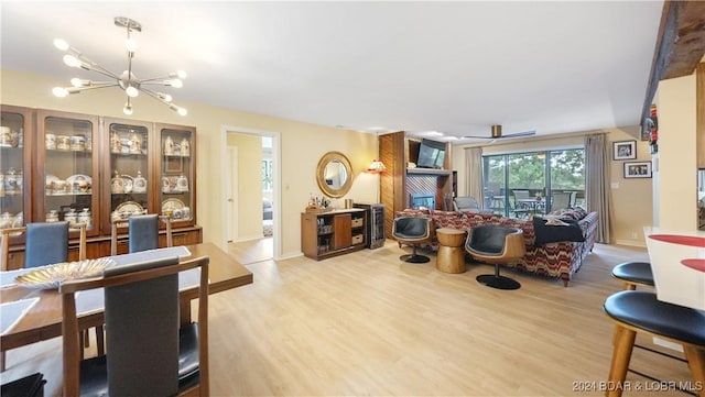 living room with a notable chandelier, a fireplace, baseboards, and wood finished floors