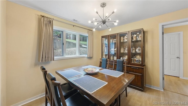 dining area with light wood-type flooring, visible vents, baseboards, and an inviting chandelier