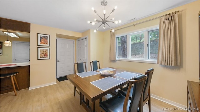 dining room with baseboards, a notable chandelier, visible vents, and light wood-style floors