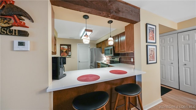 kitchen with decorative light fixtures, light hardwood / wood-style flooring, kitchen peninsula, stainless steel appliances, and decorative backsplash