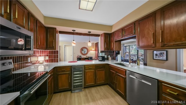 kitchen featuring sink, hanging light fixtures, stainless steel appliances, kitchen peninsula, and beverage cooler