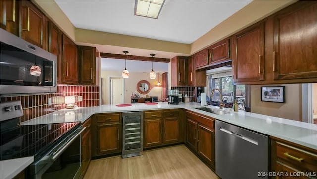 kitchen with beverage cooler, appliances with stainless steel finishes, a sink, light countertops, and backsplash