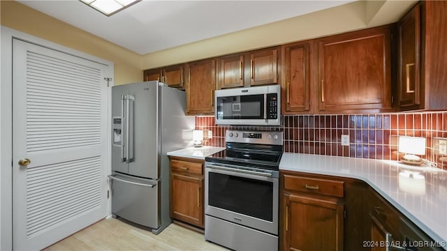 kitchen featuring brown cabinets, appliances with stainless steel finishes, light countertops, and backsplash