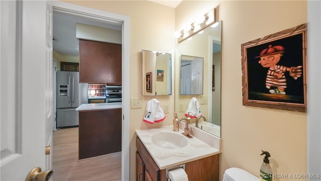 bathroom with hardwood / wood-style flooring, vanity, and toilet