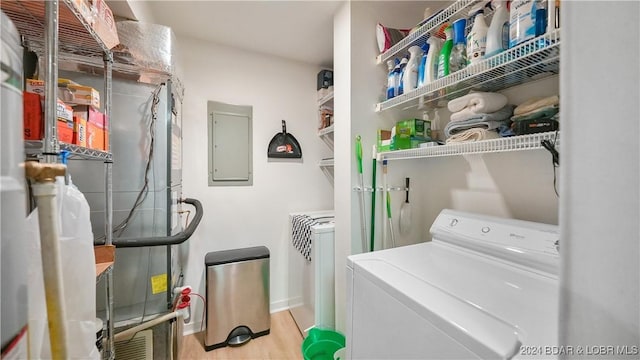 clothes washing area with washer and dryer, laundry area, electric panel, and wood finished floors