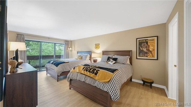 bedroom with access to exterior, light wood-style flooring, and baseboards