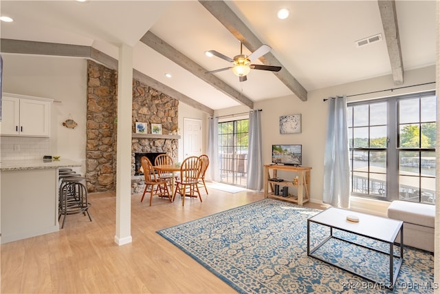 living room with light hardwood / wood-style floors, lofted ceiling with beams, a fireplace, and ceiling fan