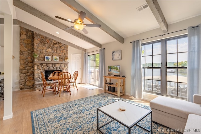 living room with ceiling fan, lofted ceiling with beams, light hardwood / wood-style flooring, and a fireplace