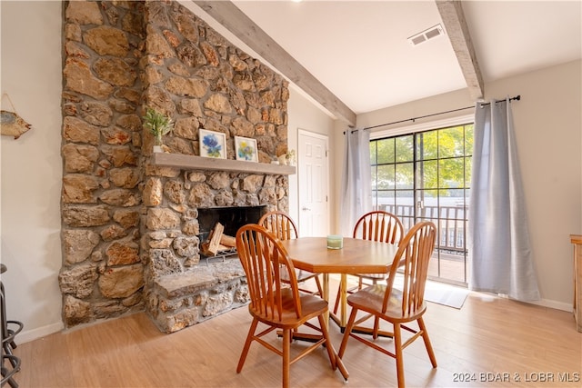 dining area with lofted ceiling with beams, light wood-type flooring, and a fireplace