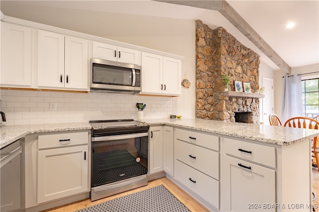 kitchen featuring kitchen peninsula, tasteful backsplash, light wood-type flooring, vaulted ceiling with beams, and stainless steel appliances