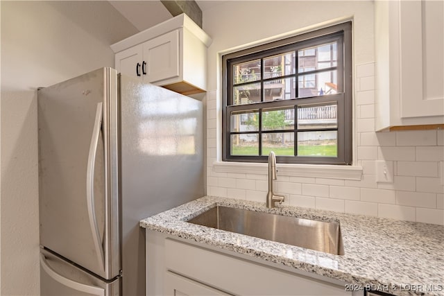 kitchen featuring white cabinetry, light stone countertops, sink, and white refrigerator