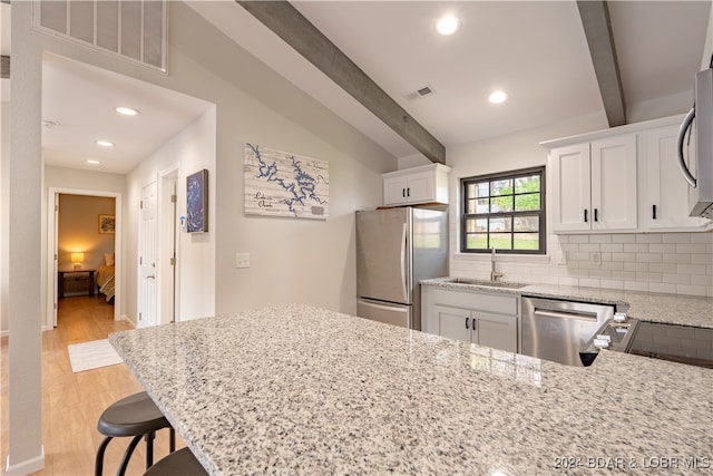 kitchen featuring light hardwood / wood-style floors, white cabinets, stainless steel appliances, and beamed ceiling