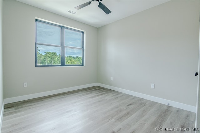 spare room featuring a ceiling fan, visible vents, light wood finished floors, and baseboards