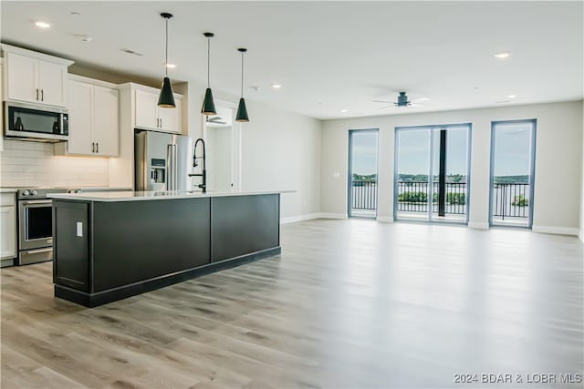 kitchen featuring open floor plan, light countertops, appliances with stainless steel finishes, and an island with sink