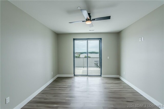 spare room with baseboards, wood finished floors, and a ceiling fan
