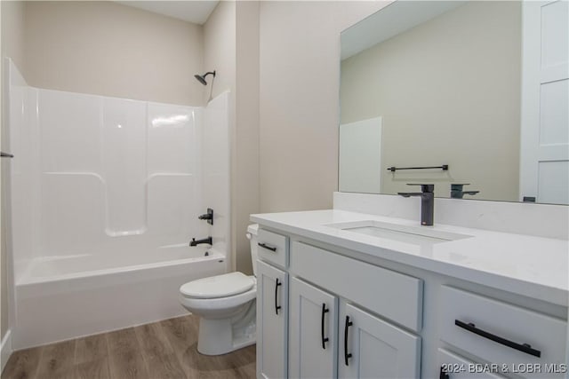 bathroom featuring wood finished floors, toilet,  shower combination, and vanity