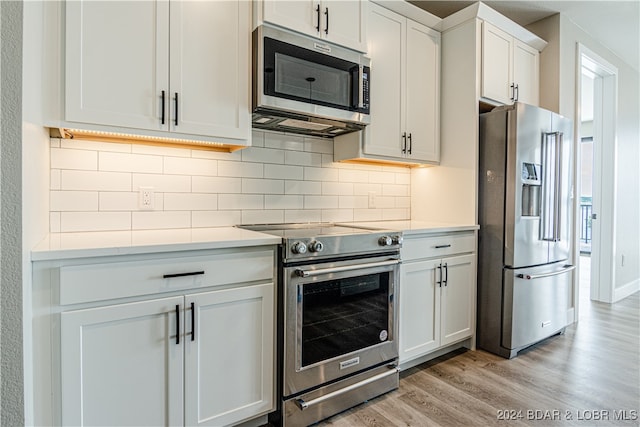 kitchen with tasteful backsplash, stainless steel appliances, light countertops, light wood-type flooring, and white cabinetry