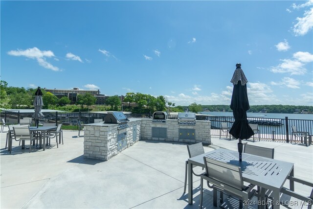 view of patio / terrace featuring exterior kitchen, outdoor dining space, a water view, and area for grilling