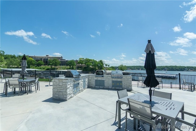 view of patio featuring a grill, fence, outdoor dining area, and an outdoor kitchen