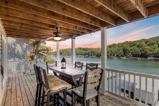 deck at dusk featuring ceiling fan and a water view