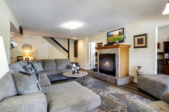 living room with a textured ceiling, dark hardwood / wood-style flooring, and a fireplace