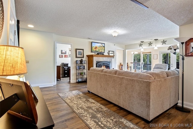 living room with dark wood-type flooring, a tile fireplace, and a textured ceiling