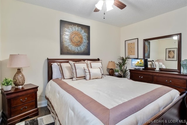 bedroom with ceiling fan, wood-type flooring, and a textured ceiling