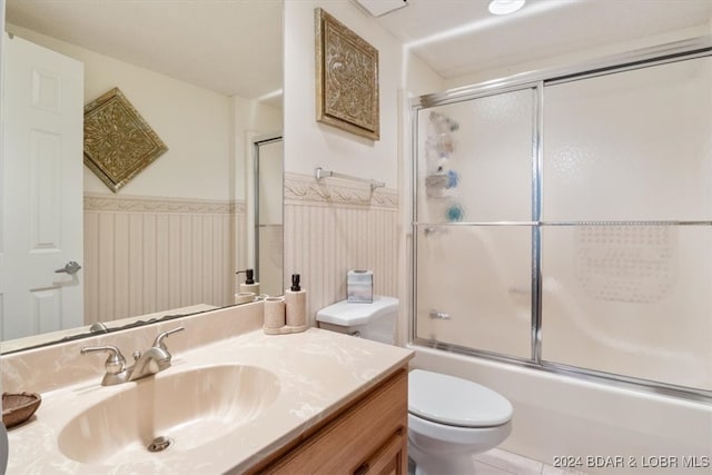 full bathroom with toilet, bath / shower combo with glass door, and vanity