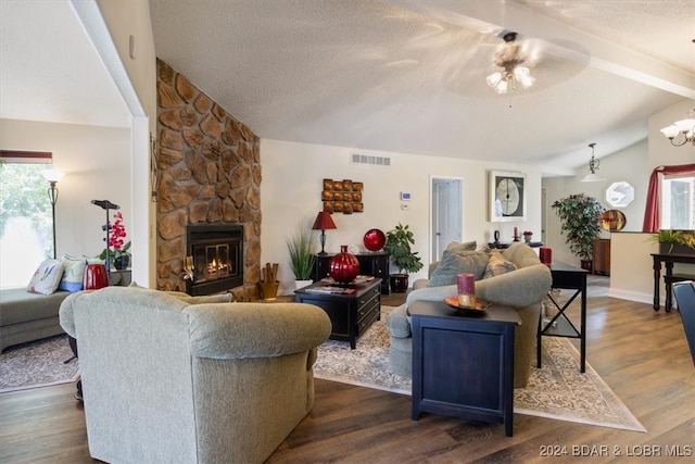 living room with a wealth of natural light, vaulted ceiling with beams, a stone fireplace, and wood-type flooring