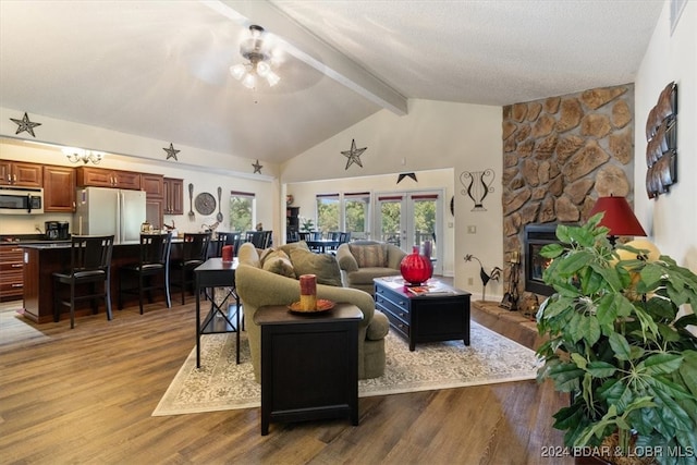 living room featuring beam ceiling, french doors, a fireplace, ceiling fan, and hardwood / wood-style flooring