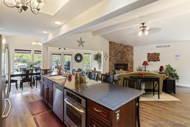 kitchen featuring dark hardwood / wood-style flooring, a fireplace, appliances with stainless steel finishes, and a kitchen island