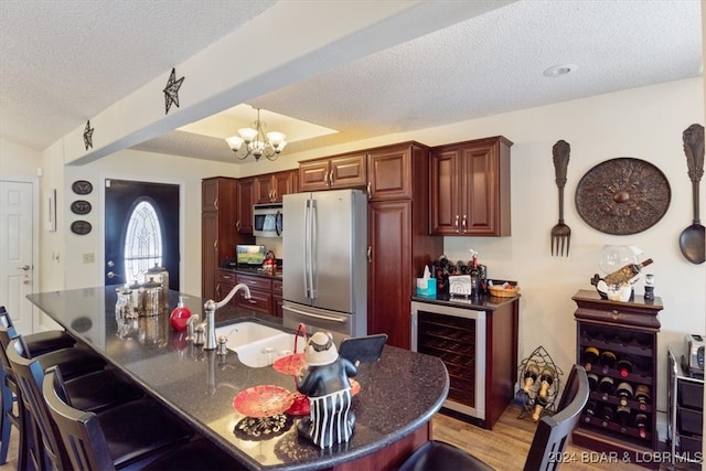 kitchen with stainless steel appliances, light hardwood / wood-style flooring, wine cooler, a textured ceiling, and a notable chandelier