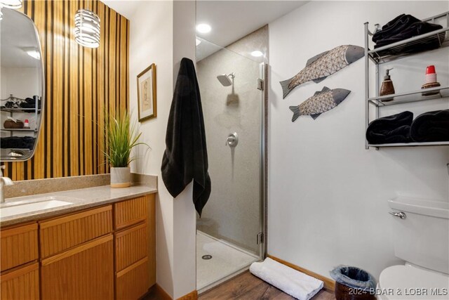 bathroom featuring hardwood / wood-style floors, toilet, a shower with door, and vanity