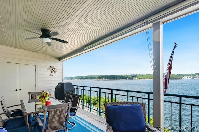 balcony with area for grilling, ceiling fan, and a water view