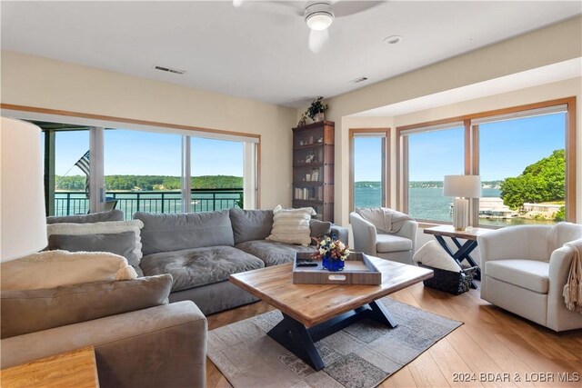 living room with a water view, ceiling fan, and light hardwood / wood-style floors