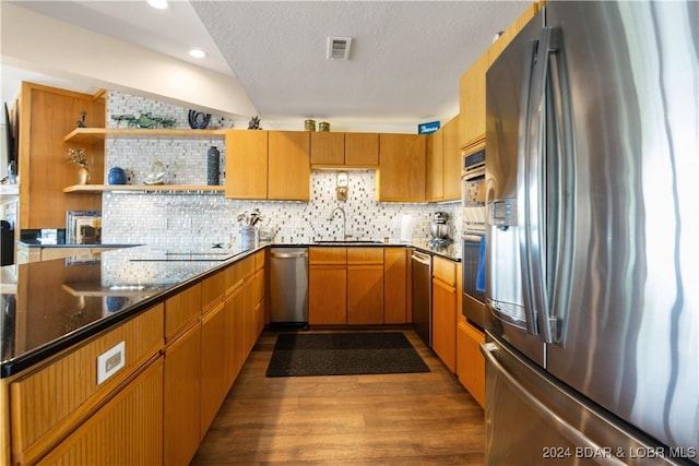 kitchen featuring appliances with stainless steel finishes, dark wood-type flooring, a sink, and backsplash