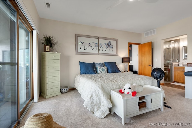 bedroom with ensuite bath and light carpet