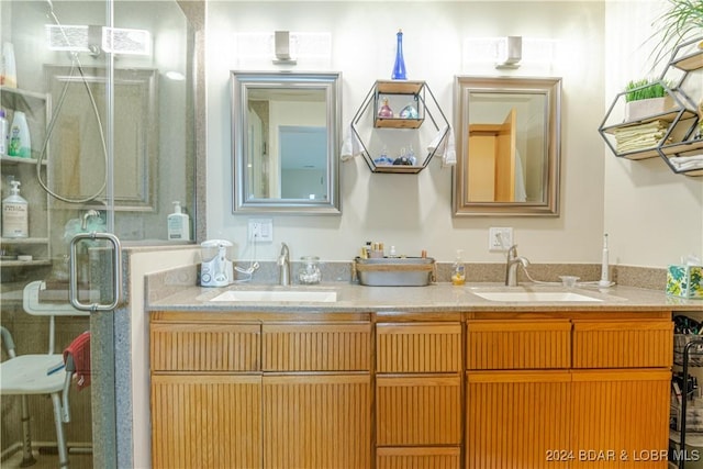 bathroom featuring double vanity, a stall shower, and a sink