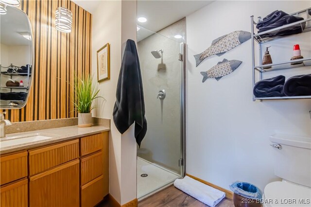 bathroom featuring a shower with door, vanity, toilet, and hardwood / wood-style flooring