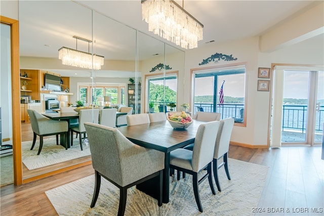 dining space featuring a fireplace, a notable chandelier, and light hardwood / wood-style floors