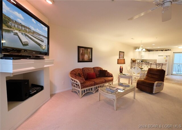 carpeted living room featuring ceiling fan with notable chandelier