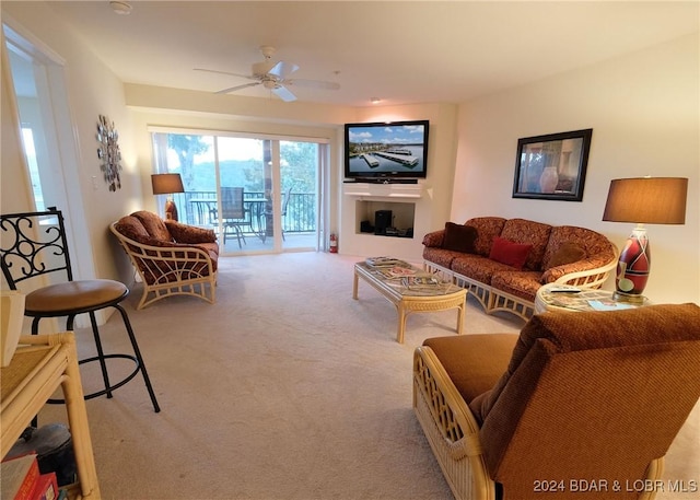 living room featuring light colored carpet, ceiling fan, and a fireplace