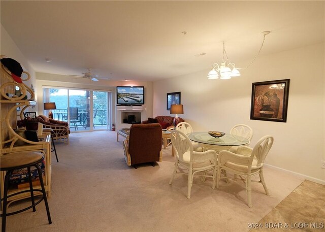 carpeted dining space featuring ceiling fan with notable chandelier