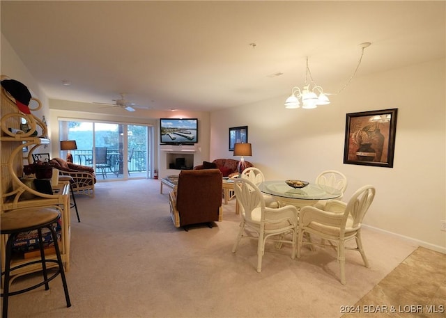 carpeted dining area with ceiling fan with notable chandelier