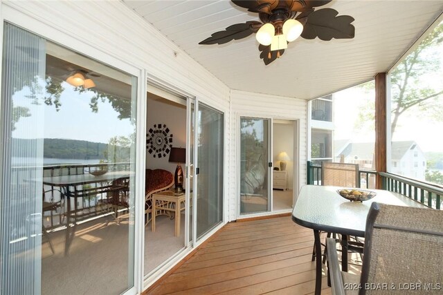 sunroom / solarium featuring ceiling fan and a water view