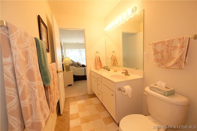 ensuite bathroom with connected bathroom, vanity, toilet, and tile patterned floors