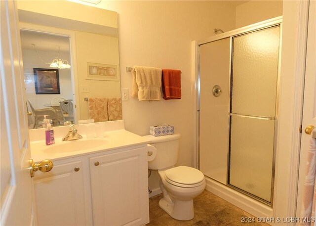 bathroom featuring an inviting chandelier, vanity, toilet, and a shower with shower door