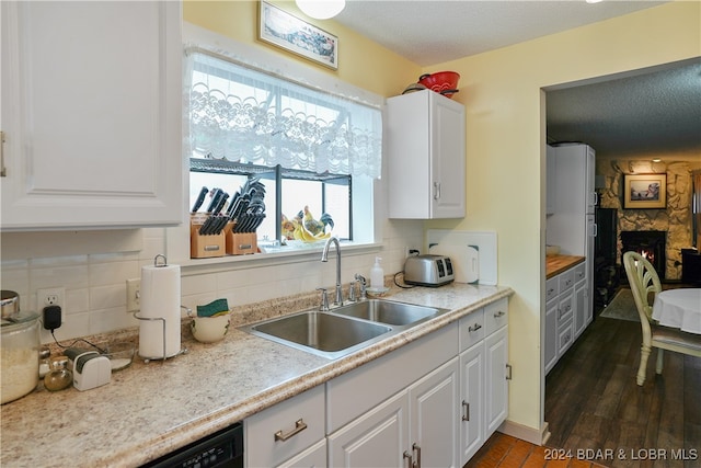 kitchen featuring sink, dark hardwood / wood-style flooring, a fireplace, tasteful backsplash, and white cabinetry